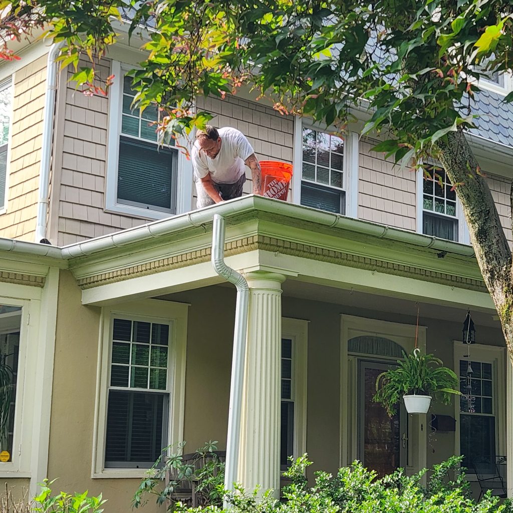 Handi Boyz crew cleaning gutters from a porch roof